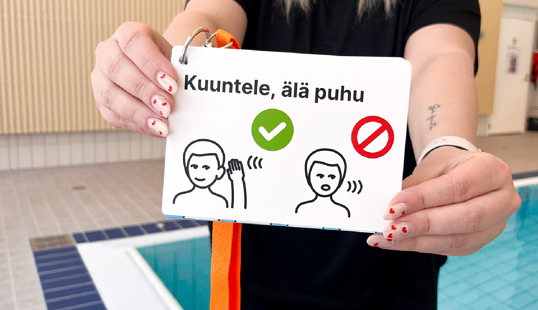 Henkilö ojentaa korttipakkaa kohti kameraa. Taustalla uima-allas.